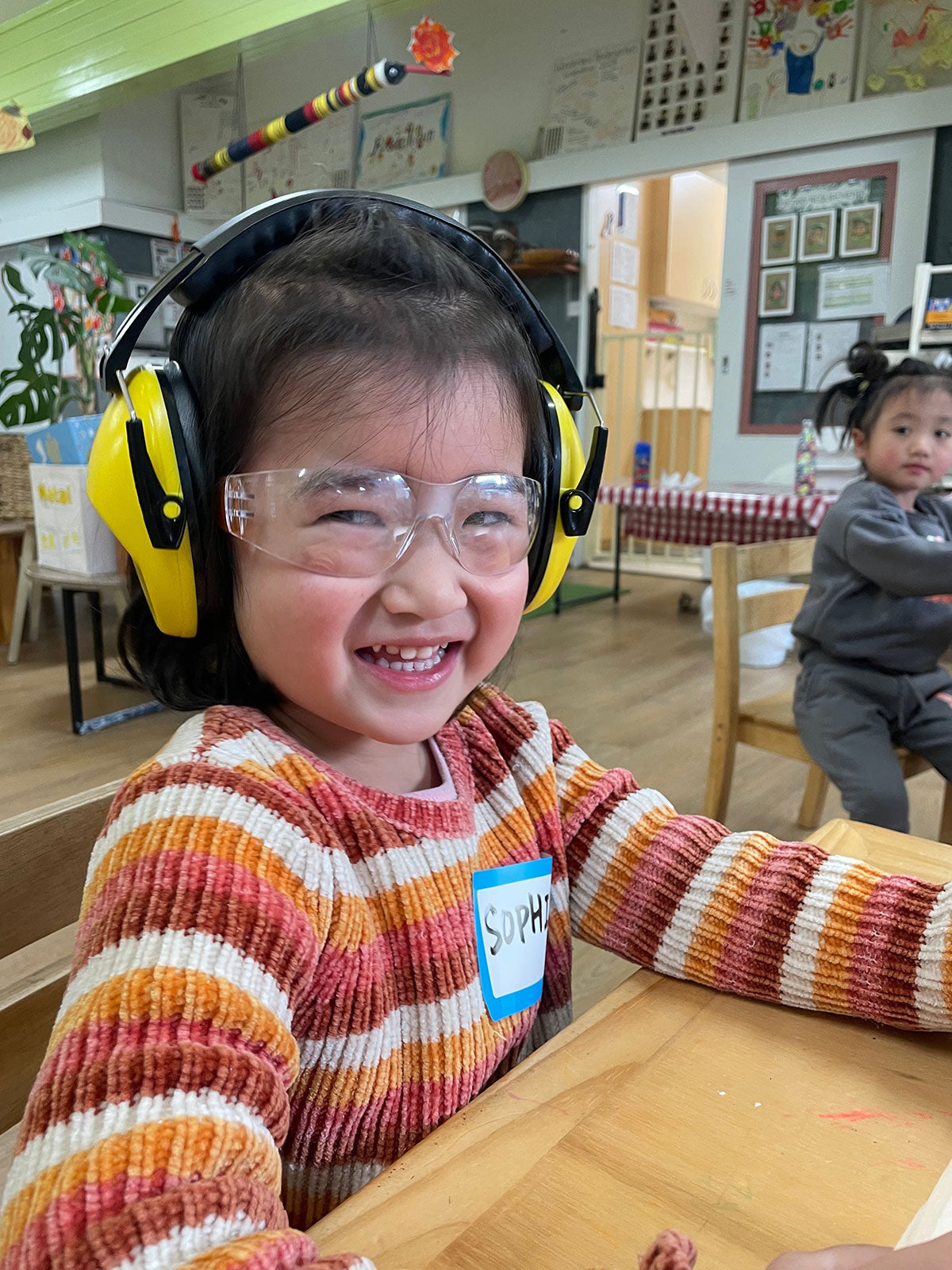 Child wearing safety goggles and ear protection in a classroom setting