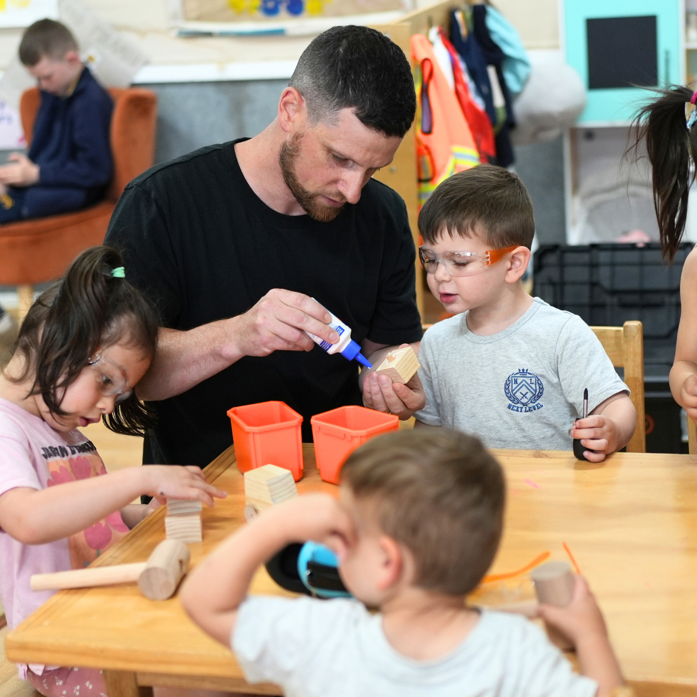 Tom and children at a table with craft materials in a classroom setting