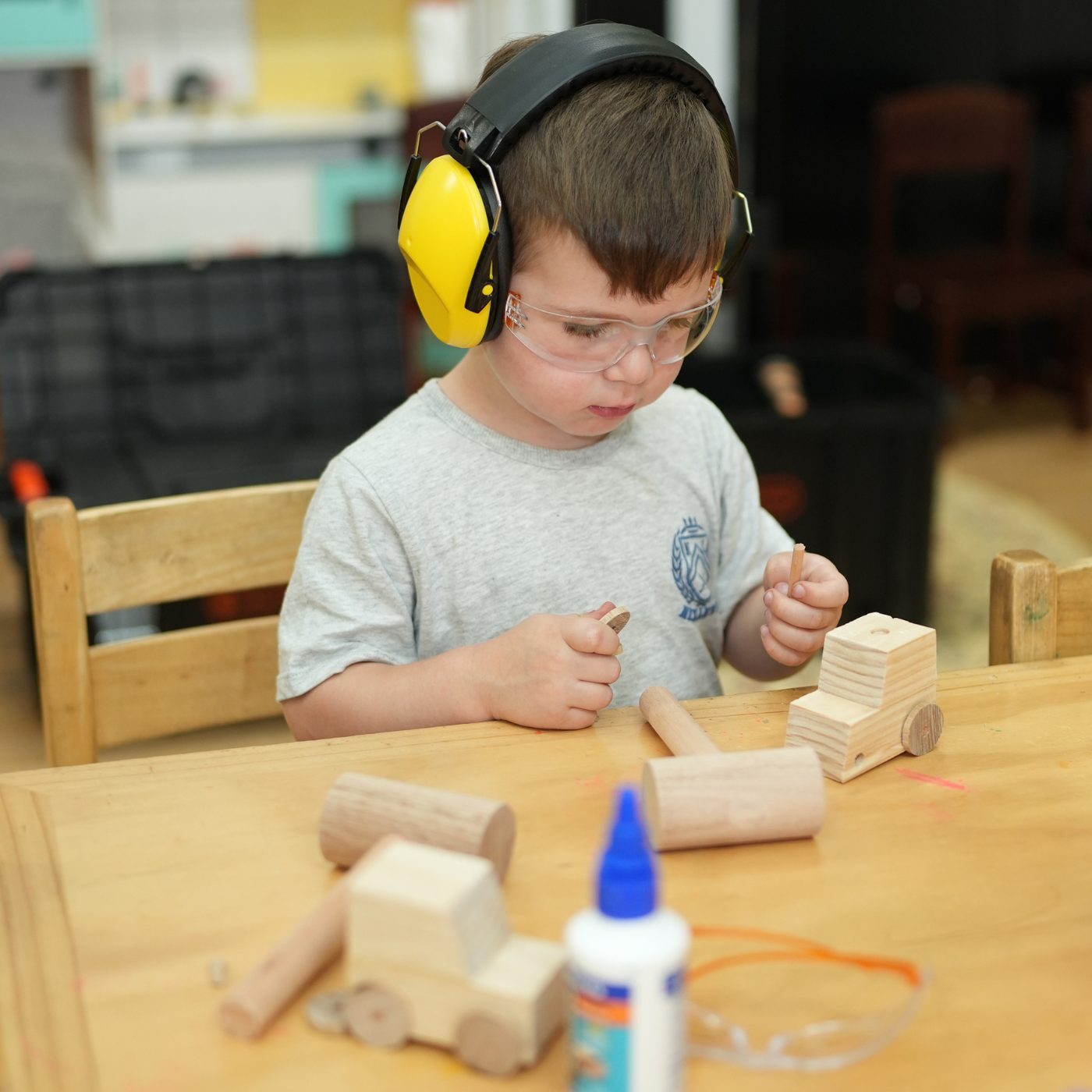 Child wearing safety goggles and learning wood craft.